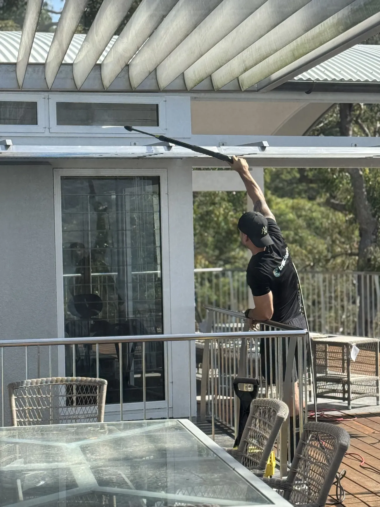 Cleaner washing windows from a balcony with a pole
